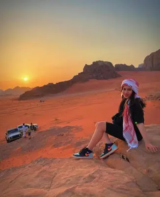 a young girl sitting on a rock in the desert at moon city with jeep trips in Wadi Rum