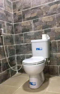 a white toilet in a bathroom with a stone wall at moon city with jeep trips in Wadi Rum
