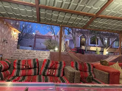 a patio with red couches sitting under a pergola at Petra Bedouin House 1 Attallah guest house in Wadi Musa