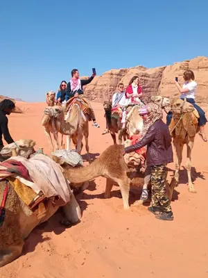 a group of people riding on camels in the desert at Bubble RumCamp in Wadi Rum