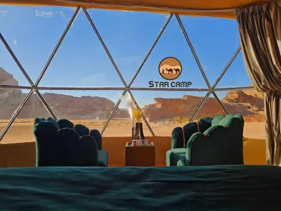 a room with chairs and a window with a view of the desert at Star Camp in Wadi Rum