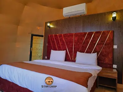a bedroom with a large bed with a red headboard at Star Camp in Wadi Rum