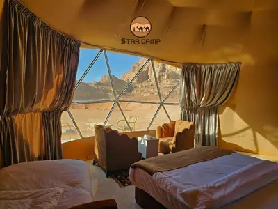 a bedroom with a bed and a large window at Star Camp in Wadi Rum
