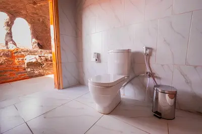 a bathroom with a toilet and a trash can at Wadi Rum Cave Camping in Wadi Rum
