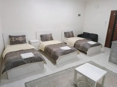 a room with three beds and a couch at For Women Only - للنساء فقط in Umm el ‘Amad