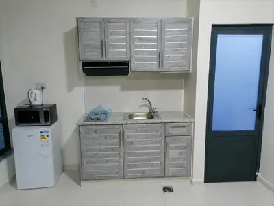 a kitchen with a sink and a microwave and a refrigerator at Durrat Al Israa in Umm el ‘Amad