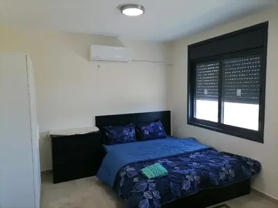 a bedroom with a bed with a blue comforter and a window at Durrat Al Israa in Umm el ‘Amad