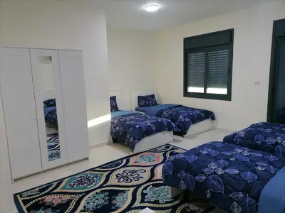 a room with three beds and a mirror at Durrat Al Israa in Umm el ‘Amad