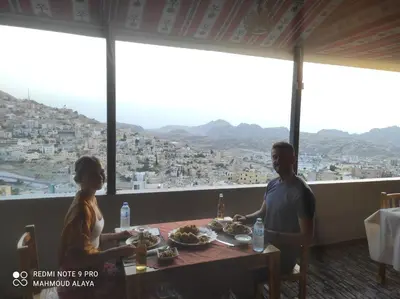 a man and a woman sitting at a table with food at Petra Wooden House in Wadi Musa
