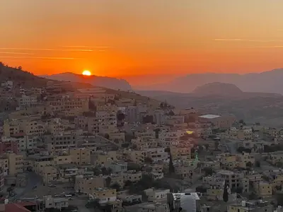 a city with the sunset in the background at Petra Wooden House in Wadi Musa