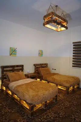 a room with three beds and a chandelier at Petra Wooden House in Wadi Musa