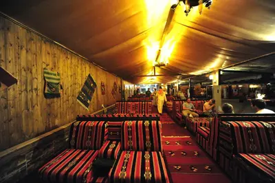 a row of red chairs in a restaurant with people at SunCity Camp in Wadi Rum