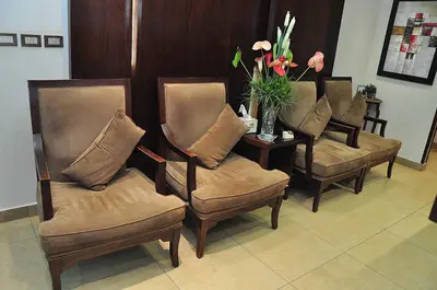 a waiting room with four chairs and a table with flowers at Bashtamal Hotel Suites in Amman