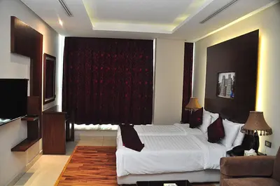 a bedroom with a large bed and a red curtain at Bashtamal Hotel Suites in Amman