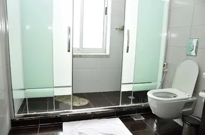 a bathroom with a toilet and a glass shower at Bashtamal Hotel Suites in Amman