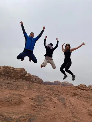a group of three people jumping in the air at Wadi Rum albasli in Wadi Rum