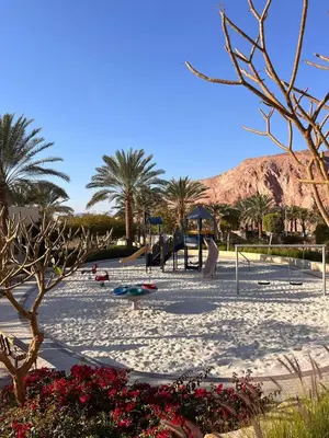 a park with a playground with palm trees and a mountain at Rental unit in RAHA village compound, special view in Aqaba