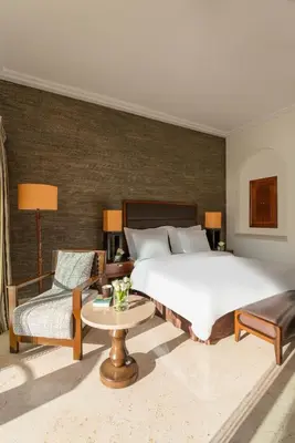 a bedroom with a large bed and a couch and a table at Mövenpick Resort & Spa Dead Sea in Sowayma