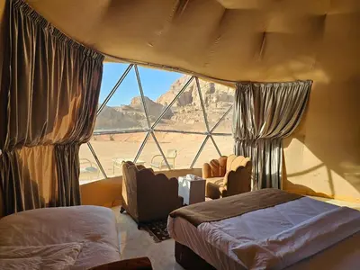 a bedroom with a large window with a view of the desert at Wadi Rum Oscar camp in Wadi Rum