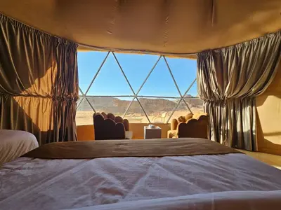 a bedroom with a bed and a large window at Wadi Rum Oscar camp in Wadi Rum