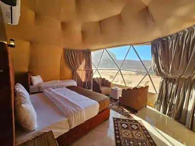 a bedroom with two beds and a large window at Wadi Rum Oscar camp in Wadi Rum