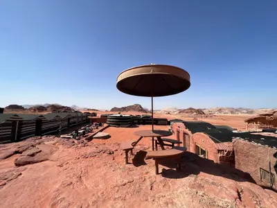 a picnic table with an umbrella in the desert at Art Camp Wadi Rum in Wadi Rum