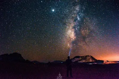 a man is looking up at the night sky at Art Camp Wadi Rum in Wadi Rum