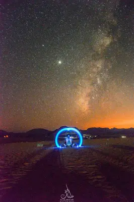 a person sitting on the beach under a starry sky at Art Camp Wadi Rum in Wadi Rum