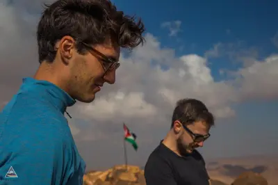 two men standing on top of a mountain at Art Camp Wadi Rum in Wadi Rum