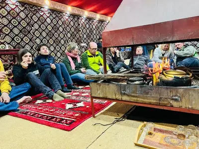 a group of people sitting next to a fire at Wadi Rum Story Camp in Wadi Rum