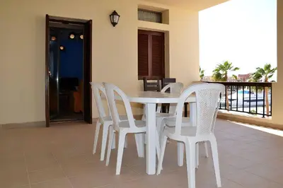 a white dining room table and chairs on a balcony at Only FAMILIES - Tala Bay Resort Aqaba - Seafront one bedroom apartment in Aqaba
