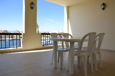 a table and chairs in a room with a large window at Only FAMILIES - Tala Bay Resort Aqaba - Seafront one bedroom apartment in Aqaba