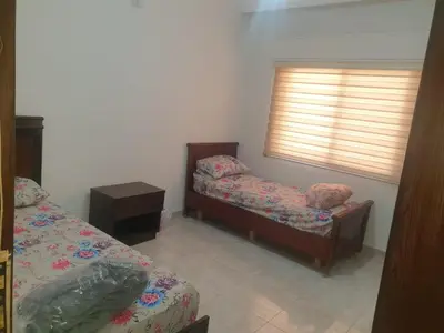 a small room with two beds and a window at شقة مفروشة فرش فاخر ٣ غرف نوم في طبربور عمان in Amman