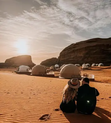 a couple sitting on the beach looking at the sunset at Orbit camp in Wadi Rum
