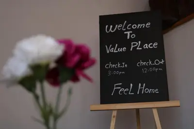 a welcome to value place sign next to a vase of flowers at VALUE PLACE in Wadi Musa