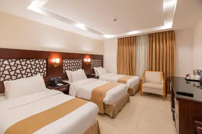 a hotel room with two beds and a chair at Petra Elite Hotel in Wadi Musa
