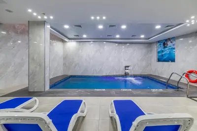 a swimming pool in a room with blue chairs around it at Petra Elite Hotel in Wadi Musa
