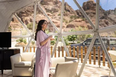 a woman in a pink dress standing in a room with chairs at The Rock Camp Petra in Wadi Musa