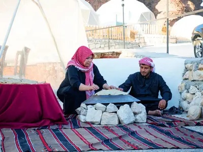 two people sitting next to a table with a cake at The Rock Camp Petra in Wadi Musa
