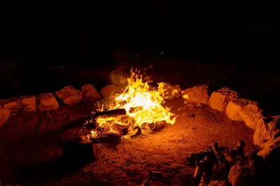 a fire burns in a fire pit at night at The Rock Camp Petra in Wadi Musa