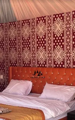 a bed with a wooden headboard with a red wall at Rum Aranda camp &Bubbles Hotel in Wadi Rum
