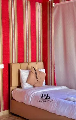 a bed in a room with a red wall at Rum Aranda camp &Bubbles Hotel in Wadi Rum