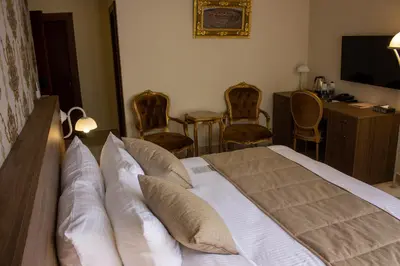 a bedroom with a bed with chairs and a television at Khan Khediwe Hotel in Amman