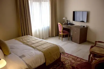 a bedroom with a bed and a desk and a television at Khan Khediwe Hotel in Amman