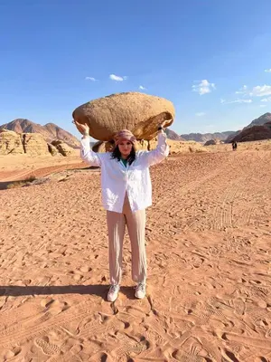 a woman in the desert holding a large rock on her head at wadi rum land mars in Wadi Rum
