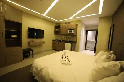 a bedroom with a white bed and a television at فندق صحارى الخليج Sahara Gulf Hotel Apartments in Amman