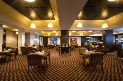 a restaurant with tables and chairs in a room at Century Park Hotel in Amman