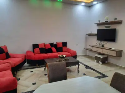 a living room with red couches and a flat screen tv at Lotus housing for furnished apartments in Jerash
