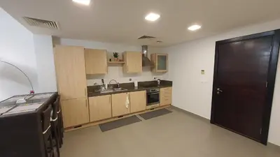 a kitchen with wooden cabinets and a black door at Comfy Stays Sea View Apartments at DeadSea Samarah Resort in Sowayma