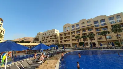 a large swimming pool with people in a hotel at Comfy Stays Sea View Apartments at DeadSea Samarah Resort in Sowayma